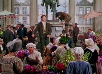 Movie still from “Hans Christian Andersen” (1952), directed by Charles Vidor – A group of people gathered around a statue of a man; Wide shot, High angle