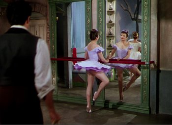Movie still from “Hans Christian Andersen” (1952), directed by Charles Vidor – A woman in a purple dress is in front of a mirror; Wide shot, Over the shoulder angle