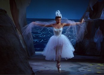 Movie still from “Hans Christian Andersen” (1952), directed by Charles Vidor – A woman in a white dress is dancing in front of the ocean; Wide shot, Low angle