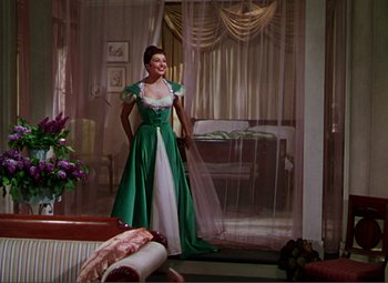 Movie still from “Hans Christian Andersen” (1952), directed by Charles Vidor – A woman in a green dress standing in a living room; Wide shot, Low angle