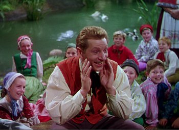 Movie still from “Hans Christian Andersen” (1952), directed by Charles Vidor – A group of people sitting around a pond with a man smiling; Medium shot, High angle