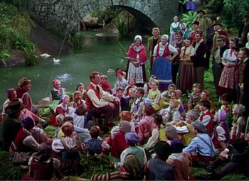 Movie still from “Hans Christian Andersen” (1952), directed by Charles Vidor – A group of people sitting around a body of water; Wide shot, High angle