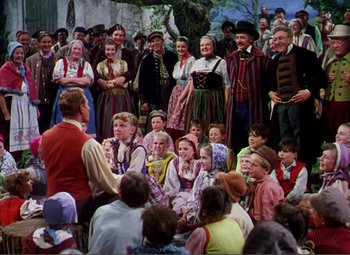 Movie still from “Hans Christian Andersen” (1952), directed by Charles Vidor – A group of people in traditional costumes are listening to a man; Wide shot, High angle