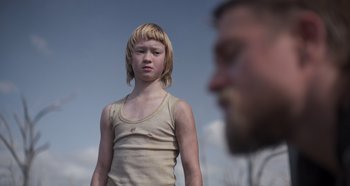 Movie still from “True History of the Kelly Gang” (2019), directed by Justin Kurzel – A young boy standing in front of a bearded man; Close Up shot, Over the shoulder angle