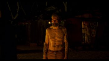 Movie still from “True History of the Kelly Gang” (2019), directed by Justin Kurzel – A man with a beard is standing in the dark; Medium shot, Over the shoulder angle