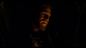 Movie still from “True History of the Kelly Gang” (2019), directed by Justin Kurzel – A man with a goatee and a beard is lit up; Close Up shot, Over the shoulder angle