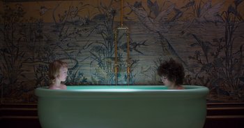 Movie still from “True History of the Kelly Gang” (2019), directed by Justin Kurzel – Two people in a bath tub in front of a mural; Wide shot, Overhead angle