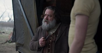 Movie still from “True History of the Kelly Gang” (2019), directed by Justin Kurzel – A man with a long beard holding a knife in his hand; Medium shot, Low angle