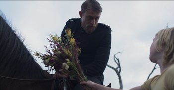 Movie still from “True History of the Kelly Gang” (2019), directed by Justin Kurzel – A man holding a bouquet of flowers while sitting on top of a horse; Medium shot, Over the shoulder angle