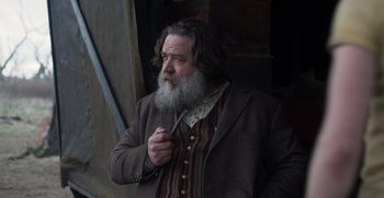 Movie still from “True History of the Kelly Gang” (2019), directed by Justin Kurzel – A man with a long beard holding a knife; Medium shot, Low angle