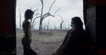 Movie still from “True History of the Kelly Gang” (2019), directed by Justin Kurzel – A man and a girl in a field near dead trees; Wide shot, Over the shoulder angle