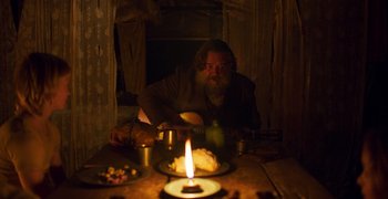 Movie still from “True History of the Kelly Gang” (2019), directed by Justin Kurzel – A man sitting at a table with a candle in the dark; Medium shot, Low angle