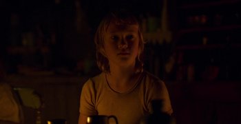 Movie still from “True History of the Kelly Gang” (2019), directed by Justin Kurzel – A little girl sitting in a dark room; Close Up shot, Over the shoulder angle