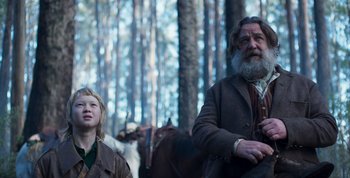 Movie still from “True History of the Kelly Gang” (2019), directed by Justin Kurzel – A man and a boy are standing in the woods; Medium shot, Low angle
