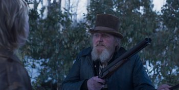 Movie still from “True History of the Kelly Gang” (2019), directed by Justin Kurzel – A man with a long beard holding a rifle; Close Up shot, Low angle