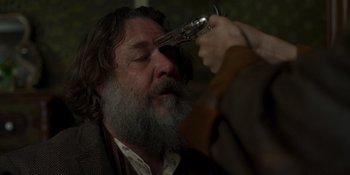Movie still from “True History of the Kelly Gang” (2019), directed by Justin Kurzel – A man with a beard and a gun in his hand; Close Up shot, Over the shoulder angle