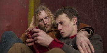 Movie still from “True History of the Kelly Gang” (2019), directed by Justin Kurzel – Two men sitting next to each other on a couch; Close Up shot, Low angle