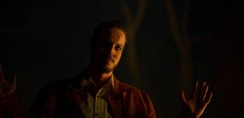 Movie still from “True History of the Kelly Gang” (2019), directed by Justin Kurzel – A man in a brown jacket standing in the dark; Close Up shot, Low angle