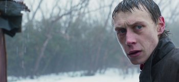 Movie still from “True History of the Kelly Gang” (2019), directed by Justin Kurzel – A man's face in the snow with trees in the background; Close Up shot, Over the shoulder angle