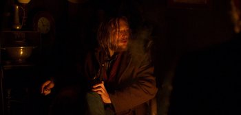 Movie still from “True History of the Kelly Gang” (2019), directed by Justin Kurzel – A man sitting in the dark with a cigarette in his mouth; Medium shot, High angle