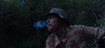 Movie still from “True History of the Kelly Gang” (2019), directed by Justin Kurzel – A man with long hair and a hat smoking a cigarette; Close Up shot, Low angle