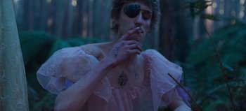 Movie still from “True History of the Kelly Gang” (2019), directed by Justin Kurzel – A person with tattoos smoking a cigarette and wearing a pirate eye patch; Medium shot, Low angle