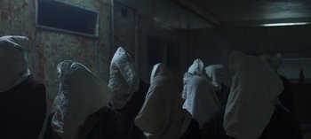 Movie still from “True History of the Kelly Gang” (2019), directed by Justin Kurzel – A group of people in a dark room covered in sheets; Close Up shot, Low angle