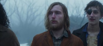 Movie still from “True History of the Kelly Gang” (2019), directed by Justin Kurzel – A man with long hair and a beard smoking a cigarette; Close Up shot, Low angle