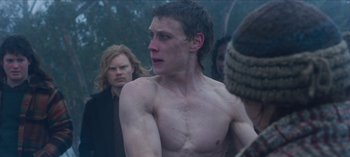 Movie still from “True History of the Kelly Gang” (2019), directed by Justin Kurzel – A man with a bare chested looks at the camera; Medium shot, Over the shoulder angle