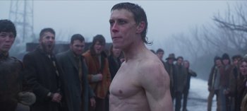 Movie still from “True History of the Kelly Gang” (2019), directed by Justin Kurzel – A shirtless man standing in front of a group of people; Medium shot, Low angle