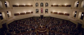 Movie still from “True History of the Kelly Gang” (2019), directed by Justin Kurzel – A large group of people gathered in a large room; Extreme Wide shot, High angle