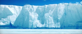 Movie still from “Happy Feet” (2006), directed by Warren Coleman – A very large wall made of ice on the beach; Extreme Wide shot, Low angle