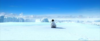 Movie still from “Happy Feet” (2006), directed by Warren Coleman – A penguin sitting in the snow on a sunny day; Extreme Wide shot, High angle