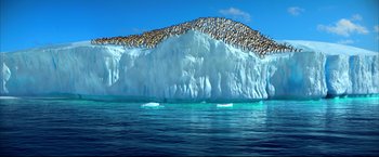 Movie still from “Happy Feet” (2006), directed by Warren Coleman – A flock of birds sitting on top of a large iceberg; Extreme Wide shot, High angle