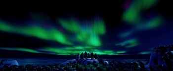 Movie still from “Happy Feet” (2006), directed by Warren Coleman – A group of people sitting on top of rocks under a cloudy sky; Extreme Wide shot, High angle