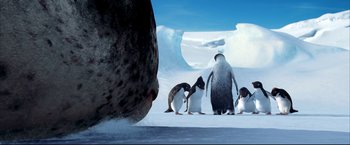 Movie still from “Happy Feet” (2006), directed by Warren Coleman – A group of penguins standing on top of a snow covered ground; Wide shot, Low angle
