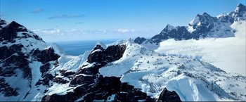 Movie still from “Happy Feet” (2006), directed by Warren Coleman – A view of a mountain range with snow on it's slopes; Extreme Wide shot, High angle