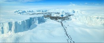 Movie still from “Happy Feet” (2006), directed by Warren Coleman – An aerial view of a snowy landscape with a herd of horses; Extreme Wide shot, High angle