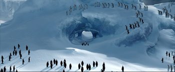 Movie still from “Happy Feet” (2006), directed by Warren Coleman – A large group of penguins in the snow near an ice cave; Extreme Wide shot, High angle