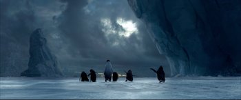 Movie still from “Happy Feet” (2006), directed by Warren Coleman – A group of penguins sitting on top of a snow covered ground; Extreme Wide shot, Low angle