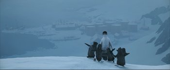Movie still from “Happy Feet” (2006), directed by Warren Coleman – A group of penguins sitting on top of a snow covered slope; Extreme Wide shot, High angle