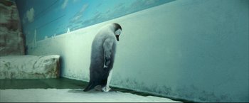 Movie still from “Happy Feet” (2006), directed by Warren Coleman – A penguin standing on the ground in front of a wall; Wide shot, Low angle