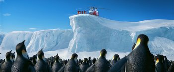 Movie still from “Happy Feet” (2006), directed by Warren Coleman – A group of penguins standing on top of a snow covered hill; Extreme Wide shot, Low angle