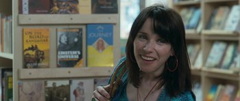 Movie still from “Happy-Go-Lucky” (2008), directed by Mike Leigh – A woman is smiling while holding a book in her hand; Close Up shot, Over the shoulder angle