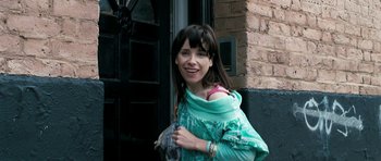 Movie still from “Happy-Go-Lucky” (2008), directed by Mike Leigh – A young woman holding a umbrella in front of a brick building; Medium shot, Low angle