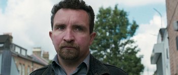 Movie still from “Happy-Go-Lucky” (2008), directed by Mike Leigh – A person with a beard; Close Up shot, Over the shoulder angle