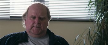 Movie still from “Happy-Go-Lucky” (2008), directed by Mike Leigh – An older man with a gray shirt is looking at the camera; Close Up shot, Low angle