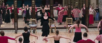 Movie still from “Happy-Go-Lucky” (2008), directed by Mike Leigh – A group of women in a room with chairs and a mirror; Wide shot, High angle