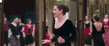Movie still from “Happy-Go-Lucky” (2008), directed by Mike Leigh – A woman in a black dress talking to a crowd of onlookers; Medium shot, Over the shoulder angle