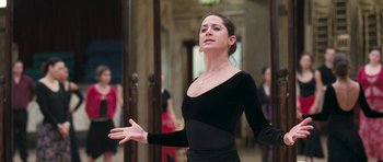 Movie still from “Happy-Go-Lucky” (2008), directed by Mike Leigh – A woman in a black dress standing in front of a group of people; Medium shot, Low angle